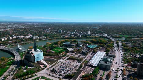 Dron-Aéreo-Toma-Cinematográfica-Caída-Centro-De-Winnipeg-Paisaje-Cielo-Horizonte-Con-Vía-Ferrocarril-Museo-Canadiense-De-Derechos-Humanos-Puente-Provencher-El-Mercado-De-Horquillas-Manitoba-Canadá