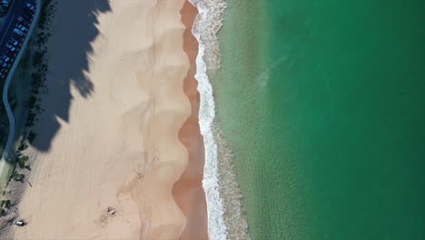 Drone-files-over-crystal-clear-blue-water-on-a-sunny-summer-day-at-Palm-Beach-near-Sydney,-Australia