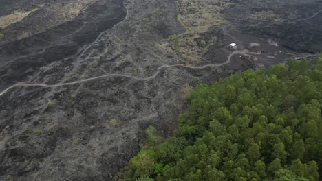 Aerial-view:-Truck-drives-on-new-road-across-expansive-dark-lava-field