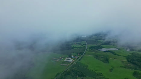 Aerial-drone-view-of-a-green-valley-that-can-be-seen-through-the-clouds