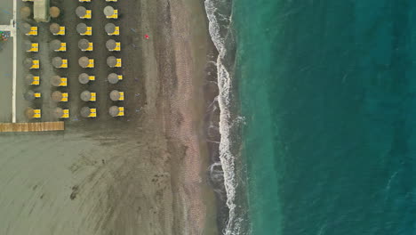 Pure-color-ocean-and-sunbeds-on-sandy-beach,-top-down-view