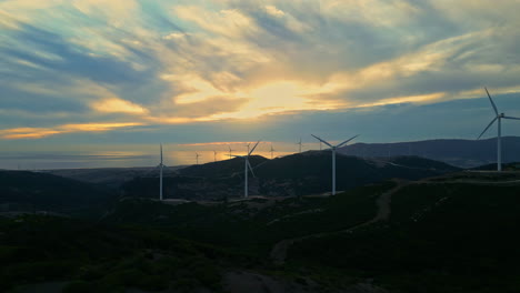 Sun-glowing-above-wind-turbine-farm-in-Spain,-aerial-view