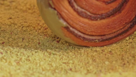 Pistachio-croissant-donut-being-rolled-over-pistachio-pieces
