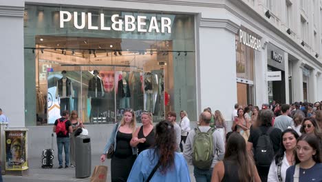 Eine-überfüllte-Straße-Voller-Käufer-Und-Fußgänger-Geht-Am-Spanischen-Multinationalen-Bekleidungsdesign-Einzelhandelsunternehmen-Inditex,-Pull-And-Bear-Store-Vorbei