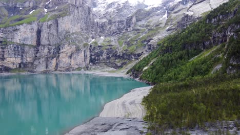 Turquoise-azure-glacial-alpine-lake-Oeschinen-surrounded-by-swiss-Blüemlisalp-mountains-in-kandersteg,-Switzerland