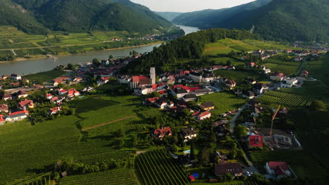 Gentle-aerial-push-in-and-rise-above-Spitz-austria-city-center-and-vineyards,-establishing-overview
