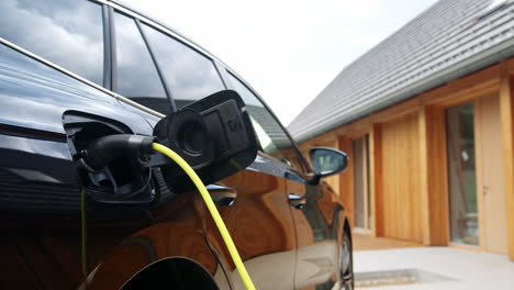 Electric-car-charging-at-home,-EV-car-with-plugged-charger,-handheld-shot