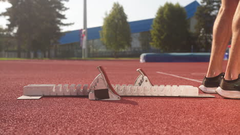 Male-sprinter-placing-legs-on-a-starting-block,-sideways-view