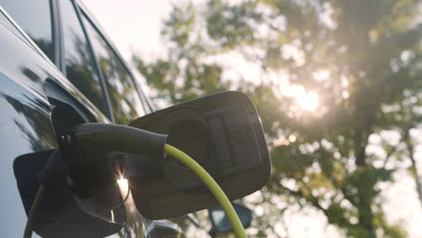 Power-cable-connected-with-a-charger-plugged-into-an-electric-car,-close-up