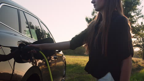 Girl-putting-a-charger-in-a-car-and-adjusting-an-EV-charging-app-on-mobile