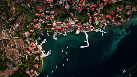 Drone-top-down-perspective-tracks-along-Ilovik-island-Croatia-coastline-port-and-village-homes