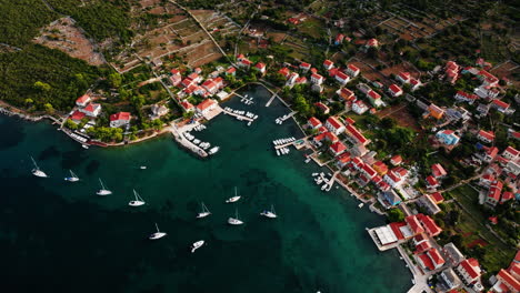 Sailboats-anchored-off-shore-of-Ilovik-island-Croatia,-bird's-eye-view-ascending-drone-shot