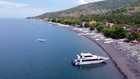 Tauchyacht-Vor-Anker-Am-Strand-Von-Amed-Mit-Jukung-Kanu-Fischerbooten-Auf-Schwarzem-Vulkansand-Im-Norden-Von-Bali,-Indonesien