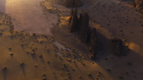 Drone-shot-tilting-backwards-in-front-of-sunlit-desert-rocks-and-cliffs,-in-KSA