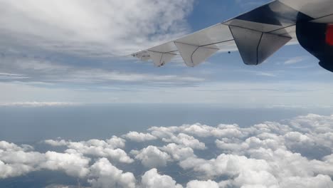 Bird's-eye-view-from-an-airplane-above-a-serene-island-and-clouds,-capturing-the-flight's-mesmerizing-journey-through-the-cloud-cover