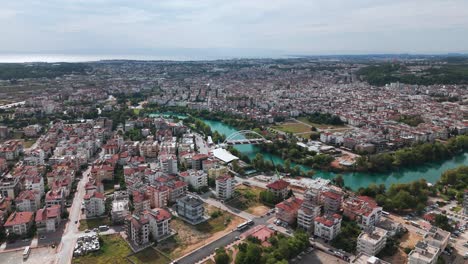 Aerial-view-approaching-archway-bridge-crossing-the-Manavgat-river-cityscape-in-the-Antalya-region-of-Turkey