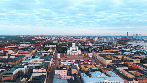 Helsinki-Cathedral-and-central-Helsinki-in-sunrise,-city-and-forest-in-background,-camera-moving-towards-and-climbing-up