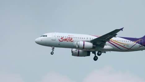 Airbus-of-Thai-Smile-Airways-almost-landing-revealing-an-air-traffic-control-tower-in-the-background-at-Suvarnabhumi-Airport-in-Bangkok,-Thailand-with-its-wheels-down