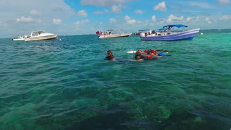 Barcos-Turísticos-Flotan-En-Las-Aguas-Tropicales-De-La-Reserva-Marina-De-Hol-Chan,-San-Pedro,-Belice,-Mientras-Los-Buceadores-Nadan-Cerca