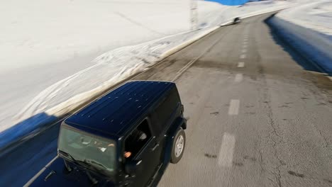 Drones-Aéreos-Fpv-Rastreando-Un-Jeep-Conduciendo-Por-Una-Pintoresca-Carretera-En-El-Paisaje-Invernal-De-Los-Pirineos