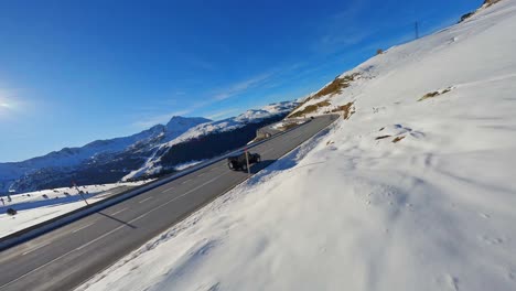 Seguimiento-Aéreo-Fpv-De-Un-Vehículo-Que-Circula-Por-Una-Carretera-Panorámica-En-Un-Paisaje-Montañoso-Cubierto-De-Nieve