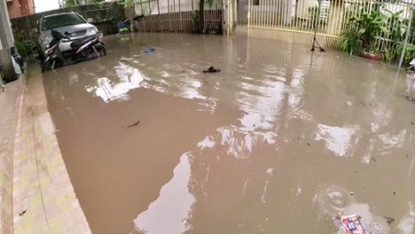 Agua-Turbia-De-Inundación-En-El-Patio-De-La-Casa-Y-Zapato-Flotante-Después-De-Lluvias-Torrenciales-En-El-Centro-Turístico-De-Siem-Reap,-Camboya