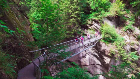 Hikers-walking-across-a-metal-bridge-on-the-Passer-Gorge-trail-is-in-the-Passeier-Valley-in-South-Tyrol,-Italy