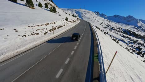 FPV-racing-drone-tracking-a-vehicle-driving-along-a-picturesque-mountain-highway-in-the-Pyrenees