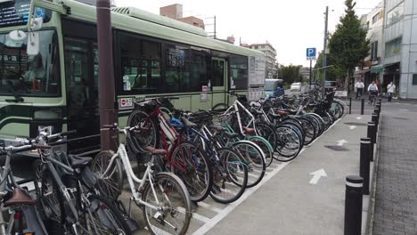 Estacionamiento-De-Bicicletas-Y-Tráfico-Callejero-En-Kioto,-Japón,-Personas-Que-Conducen-Autobuses-En-Verano-En-La-Estación-Demachiyanagi,-Barrio-De-Sakyo