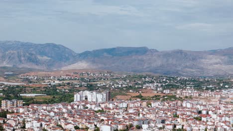 Panoramic-aerial-view-across-Side,-Turkey-resort-town-and-South-Eastern-mountain-range-across-the-ancient-skyline