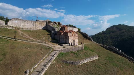 Monumentos-Antiguos-En-La-Ciudad-De-Berat:-Antiguas-Murallas-De-La-Iglesia-Y-El-Castillo-En-La-Colina-Junto-Al-Río,-Explorando-El-Patrimonio-De-La-Unesco-En-Albania