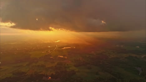 Wunderschöne-Luftaufnahme-Des-Warmen-Sonnenlichts,-Das-Durch-Die-Wolken-über-Der-Landschaft-Unten-In-Lettland-Strahlt
