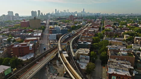Aerial-view-backwards-over-CTA-trains-on-elevated-rails,-golden-hour-in-Wrigleyville,-Chicago