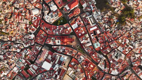 Top-down-drone-shot-above-the-cityscape-of-Guanajuato,-golden-hour-in-Mexico