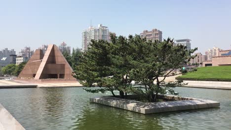 Monument-in-Longhua-Gardens-Park-near-Martyrs-Memorial-in-Shanghai,-China-with-a-tree-in-a-water-pool