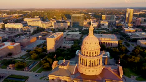 Centro-De-Austin,-Edificio-De-La-Capital-Del-Estado-De-Texas,-Disparo-Aéreo-De-Un-Dron-Rodeando-La-Cúpula-Con-La-Estatua-De-La-Diosa-De-La-Libertad-En-La-Parte-Superior-Con-Vistas-A-La-Universidad-De-Texas-En-El-Campus-De-Austin,-Horizonte-Al-Atardecer-En-4k