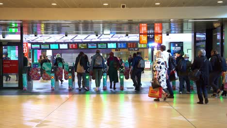 Peak-hours-at-Brisbane-City-Central-Station,-commuters-rushing-their-way-towards-the-platform,-passing-through-gates-and-paying-fares-by-tapping-their-go-card-or-credit-card-on-the-machines