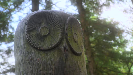Owl-wooden-sculpture-closeup-in-English-woodland-with-very-slow-zoom-out