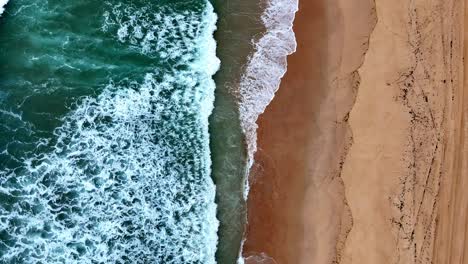 Ein-Strand-Mit-Einer-Welle,-Die-Ans-Ufer-Strömt,-Und-Ein-Sandstrand-Mit-Einem-Grünen-Ozean-Und-Einem-Sandstrand