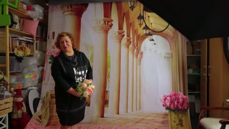 Slavic-woman-posing-in-old-outdated-photo-studio-in-front-of-poster-with-Greek-columns