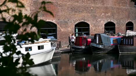 People-walking-past-boats-on-the-Regents-Canal,-London,-United-Kingdom