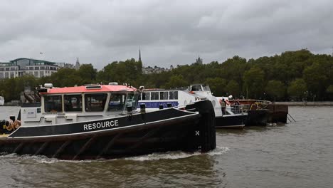 Resource-and-other-boats-passing-the-Emerald-of-London-boat,-London,-United-Kingdom