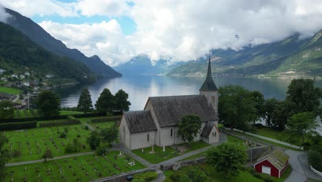 Ullensvang-Church-and-Headstones-in-Hardangerfjord,-Vestland,-Norway---Aerial-Circling