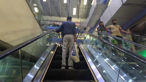 Die-Leute-Gehen-Mit-Dem-Automatischen-Rolltreppenaufzug-In-Das-Einkaufszentrum-Und-Viele-Leute-Kommen-Nach-Dem-Einkaufen-Wieder-Heraus