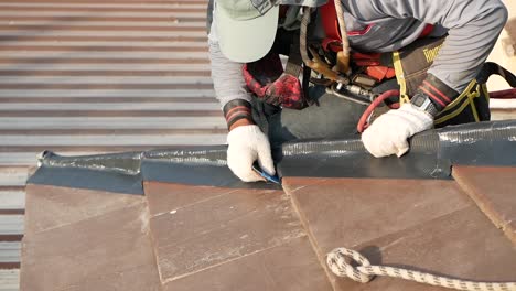 Trabajador-Asiático-Puso-Cinta-Impermeable-En-El-Borde-De-Las-Tejas,-De-Cerca