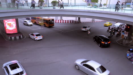 Footage-of-vehicles-crossing-this-intersection-of-Rama-I-Road-and-Phaya-Thai-Road,-above-is-the-Pathum-Wan-Skywalk,-at-MBK-and-Bangkok-Culture-and-Arts-Center,-Thailand