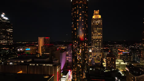 Rising-drone-shot-showing-luxury-Westin-Peachtree-Plaza-Tower-lighting-at-night-in-Atlanta-City