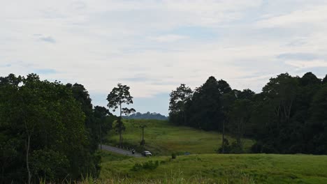 Zoom-out-of-this-lovely-landscape-in-Khao-Yai-National-Park-in-Thailand-revealing-cars-moving-to-the-right-during-a-cloudy-afternoon