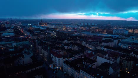 Drone-aerial-shot-of-Stockholm-skylin,-Sweden-on-a-cloudy-evening-with-sunset-coming-through