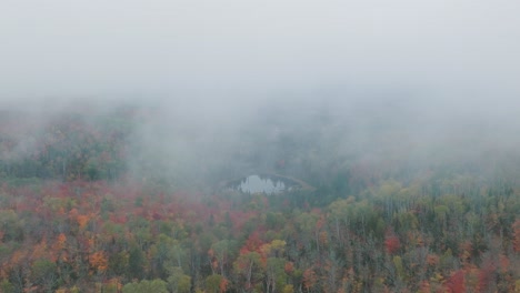 Drohne-Fliegt-Durch-Neblige-Wolken-Und-Enthüllt-Herbstwald-Und-Teich